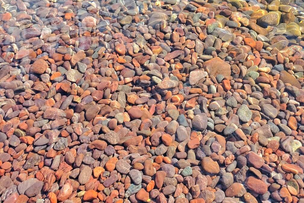 Things to do in the Keweenaw Peninsula: colorful red and purple rocks at beach in Astor Shipwreck Park in Copper Harbor. Upper Peninsula. UP Michigan travel blog