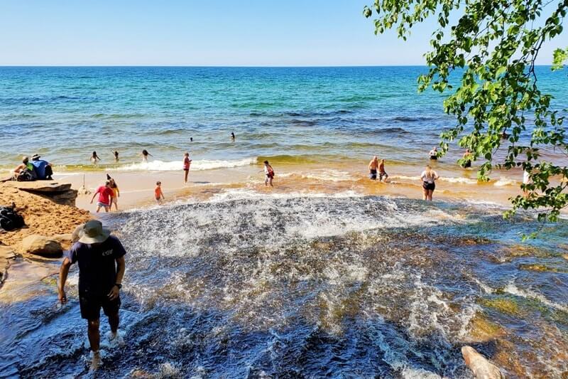 Things to do in Pictured Rocks National Lakeshore park: chapel beach falls, waterfalls flowing into lake superior. UP Michigan travel blog