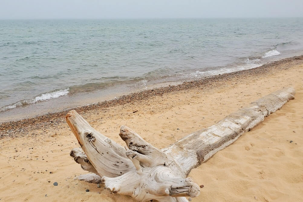 Whitefish Point beach near whitefish point lighthouse. Lake Superior lighthouse shipwreck coast. upper peninsula. up michigan travel blog