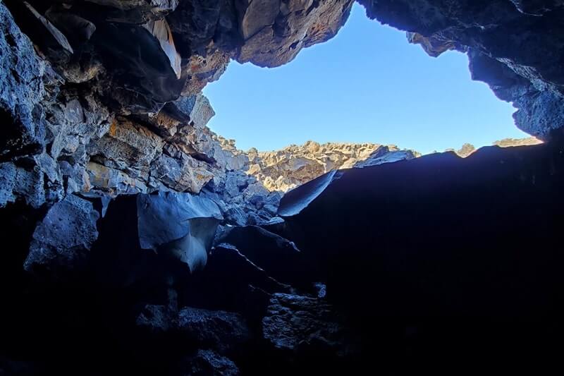climbing out of Dewdrop Cave lava tube. dewsdrop cave opening. craters of the moon. idaho travel blog