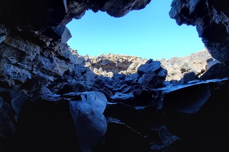 climbing out of Dewdrop Cave lava tube. dewsdrop cave opening. craters of the moon. idaho travel blog