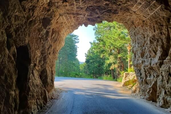 CC Gideon Tunnel view of Mount Rushmore on Iron Mountain Road. Driving through Iron Mountain Road tunnel to see Mount Rushmore. black hills national forest. south dakota travel blog