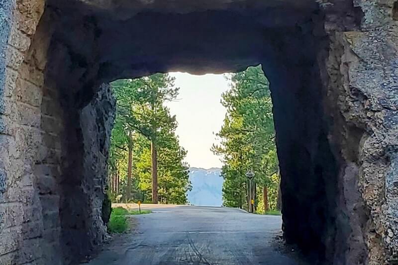 Scovel Johnson Tunnel view of Mount Rushmore on Iron Mountain Road. Driving through Iron Mountain Road tunnel to see Mount Rushmore. black hills national forest. south dakota travel blog