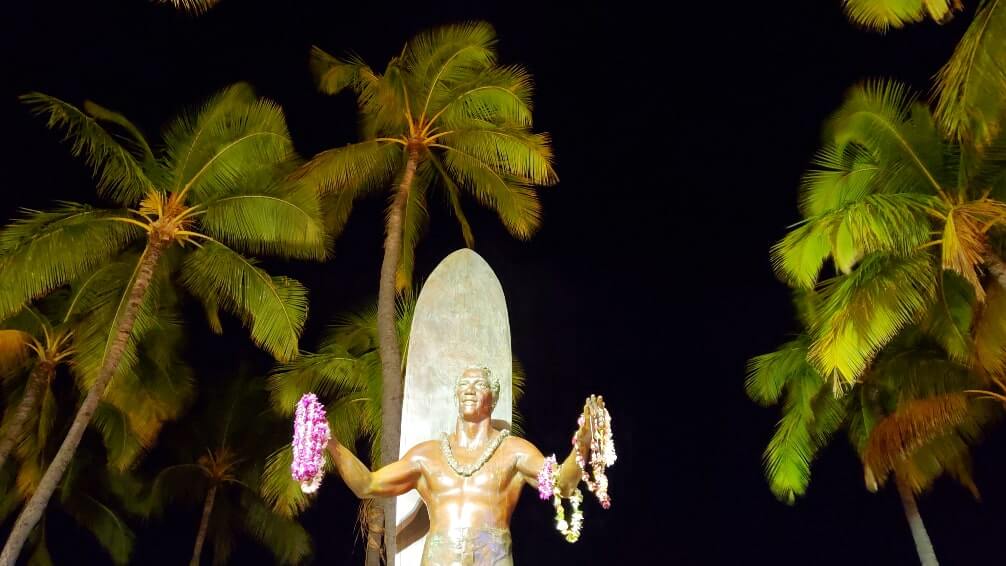 things to do in waikiki at night: duke kahanamoku statue. waikiki surfer statue at night. honolulu at night. oahu at night. hawaii travel blog