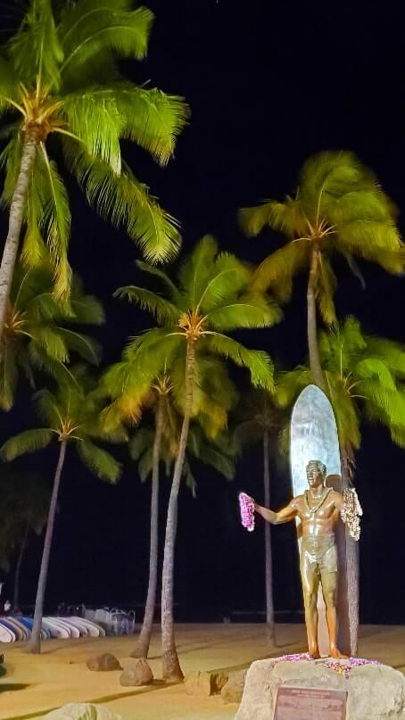 things to do in waikiki at night: duke kahanamoku statue. waikiki surfer statue at night. honolulu at night. oahu at night. hawaii travel blog